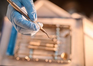 Gloved hand holding dental instrument